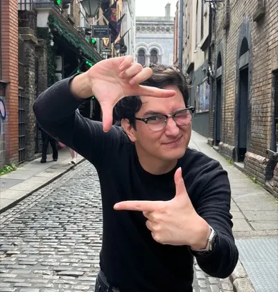 Chris framing his face with his hands on a cobblestone street